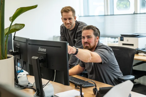 Collega Flexcom wijst op scherm, dat perfecte werkplek weergeeft